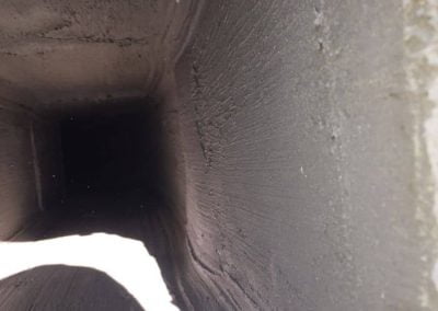 A view inside a dusty, rectangular chimney or vent shaft with light and shadows on the interior walls.