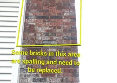 A brick chimney with a highlighted area showing spalling bricks that need replacement.