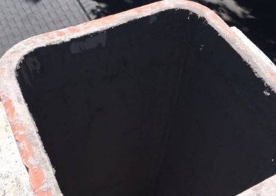 A close-up view of the top of an empty rectangular chimney with sunlight and shadows.