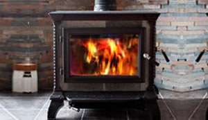 Wood-burning stove with a glass door showing flames inside, set against a tiled wall, perfect for warming up your Knowledge Center.