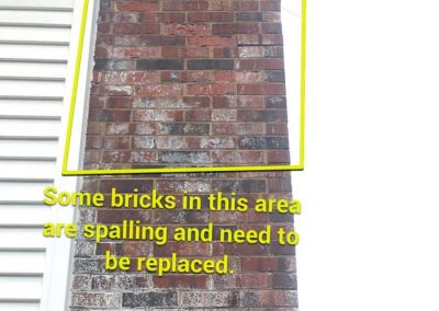 A brick chimney with a highlighted area showing spalling bricks that need replacement.