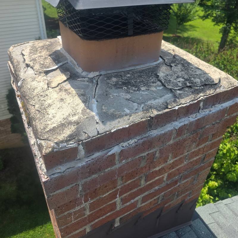 Severely cracked and flaking chimney crown with failed patch repairs