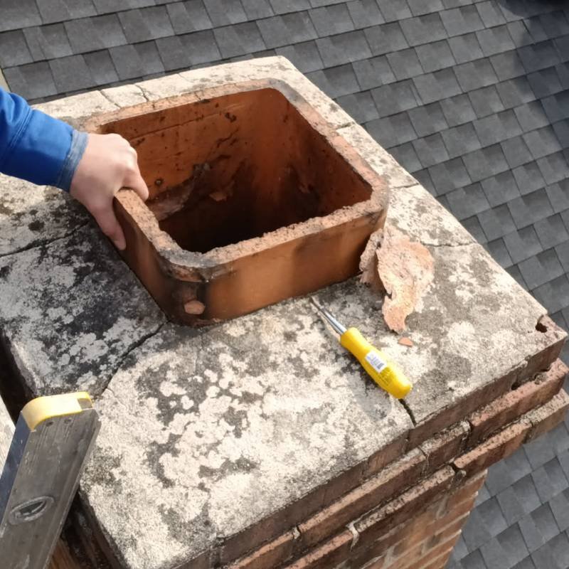 Technician examining a cracked chimney crown and flue tile