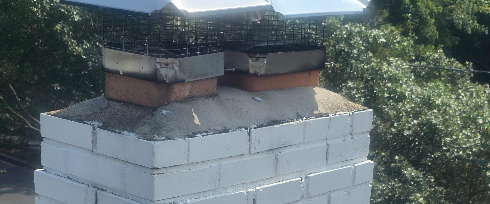 Masonry chimney with stainless steel caps seen from the rooftop