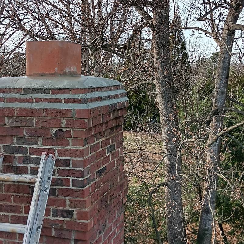Freshly rebuilt concrete chimney crown with flue tile extending above it