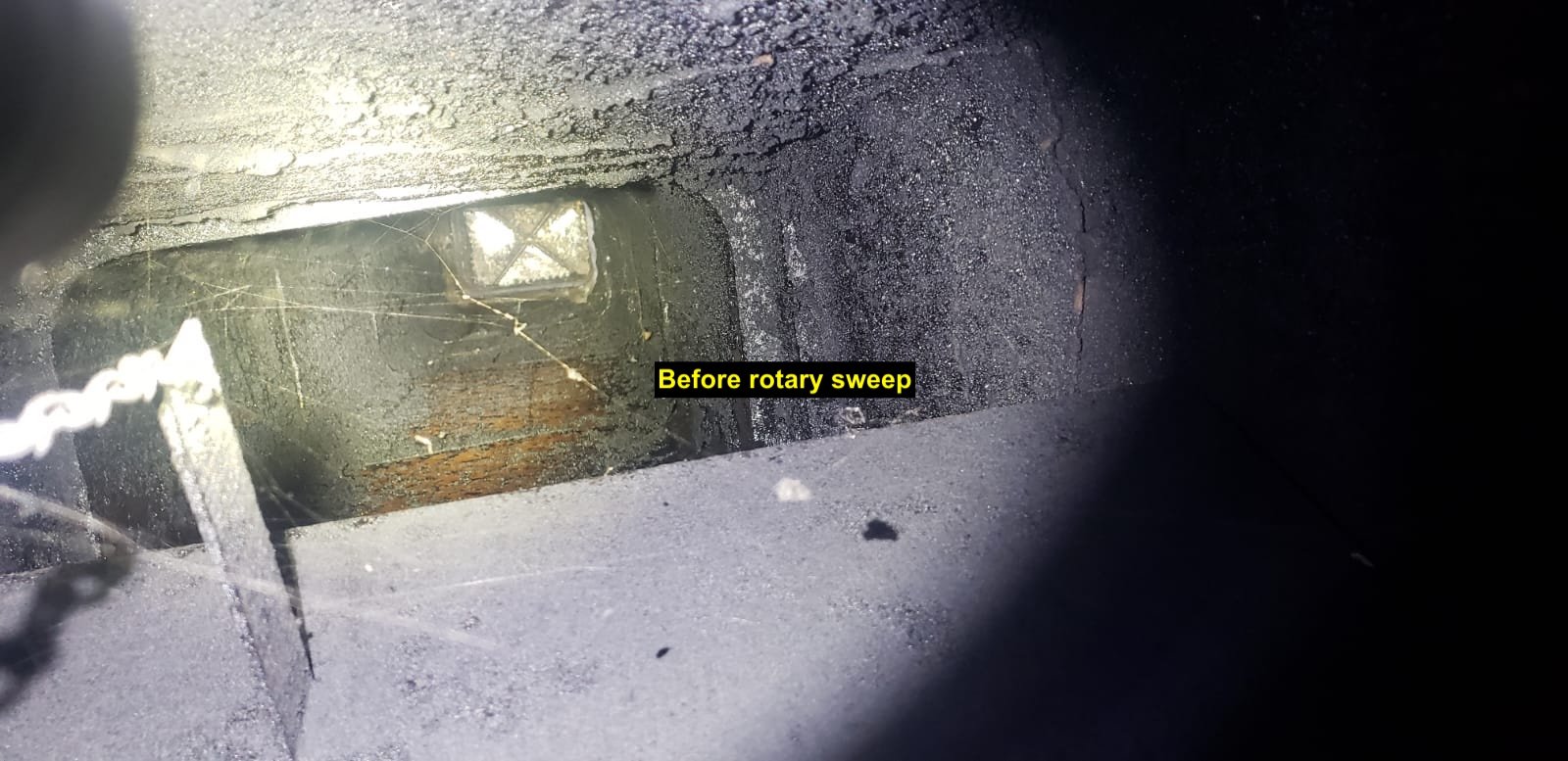 Heavy creosote buildup in a smoke chamber before rotary sweeping