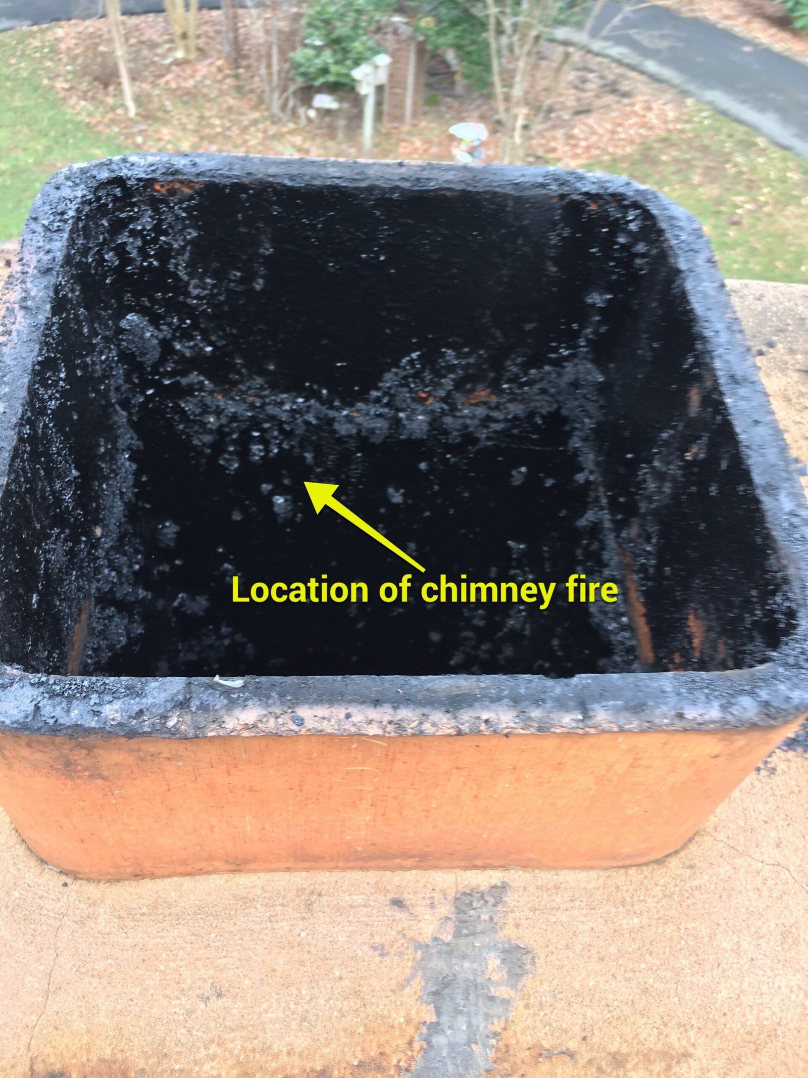 Flue tile coated in burned creosote with annotation marking the location of a chimney fire