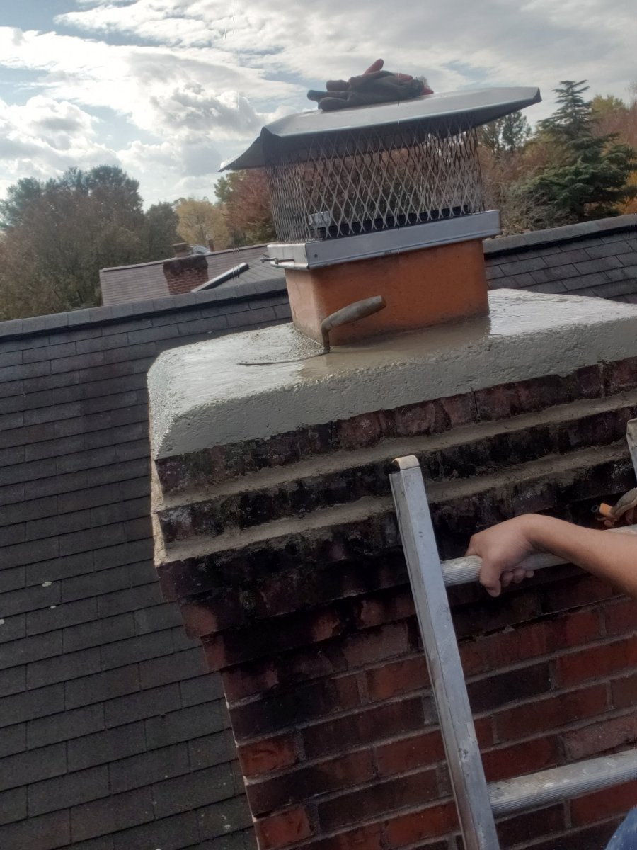 Chimney crown being rebuilt with fresh concrete, trowel still on the crown